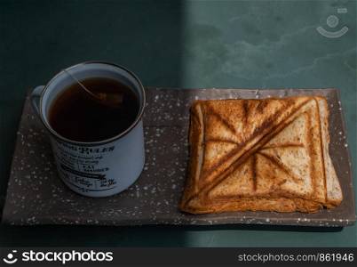 Breakfast - sandwiches and Cup of tea on a ceramics salver. Oblique view from the top.