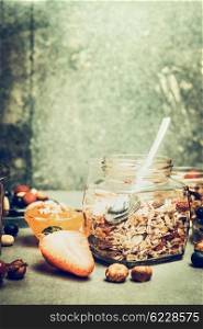 Breakfast scene with muesli jar on kitchen table with nuts and berries over rustic background, place for text, retro toned