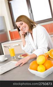 Breakfast - Smiling woman reading newspaper in kitchen, with coffee and fresh orange juice
