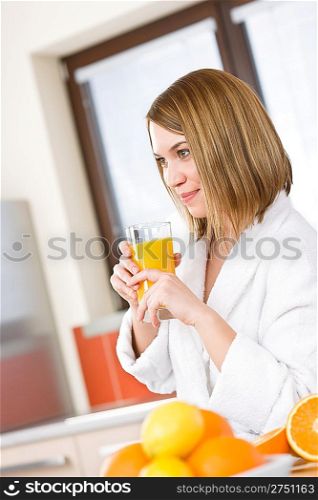 Breakfast - Smiling woman with fresh orange juice in modern kitchen