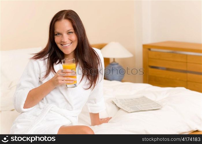 Breakfast - Smiling woman with fresh orange juice in white bedroom