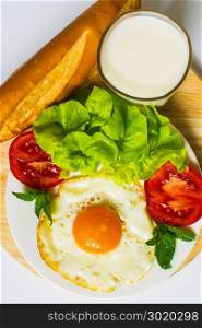 Breakfast with bread, fried eggs, milk and vegetables and fried tomato pieces isolated on white background