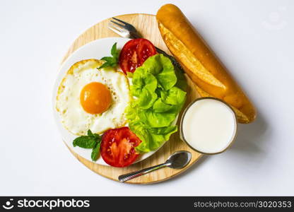 Breakfast with bread, fried eggs, milk and vegetables and fried tomato pieces isolated on white background