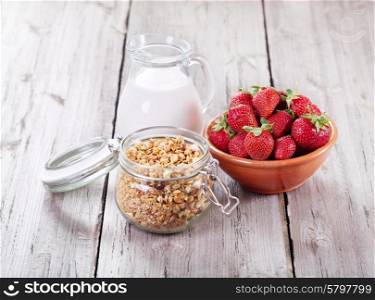 breakfast with cereals, milk and strawberries on wooden table