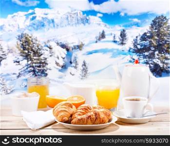 breakfast with coffee and croissants on wooden table over winter landscape