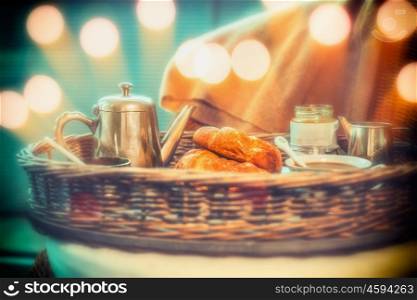 Breakfast with coffee pot and croissants on tray with bokeh lighting