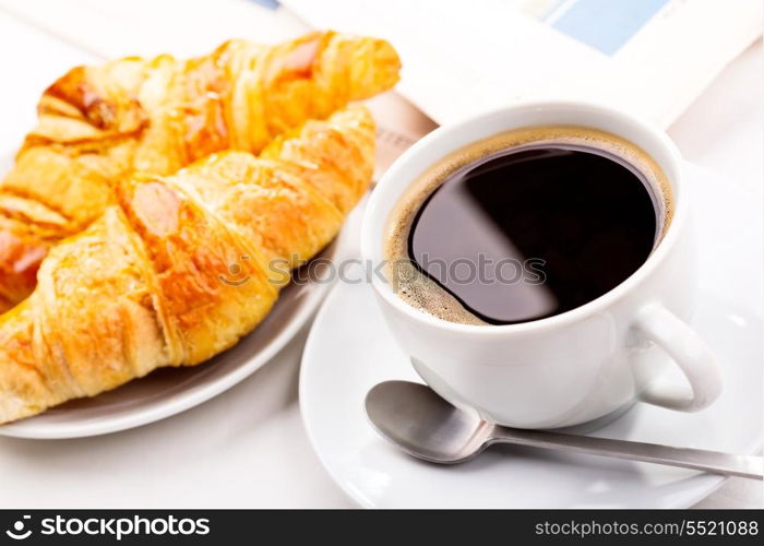 breakfast with cup of black coffee, croissants and newspaper