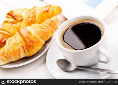 breakfast with cup of black coffee, croissants and newspaper