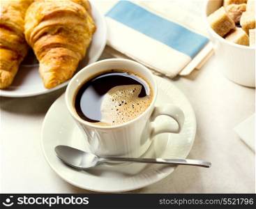 breakfast with cup of black coffee, croissants and newspaper
