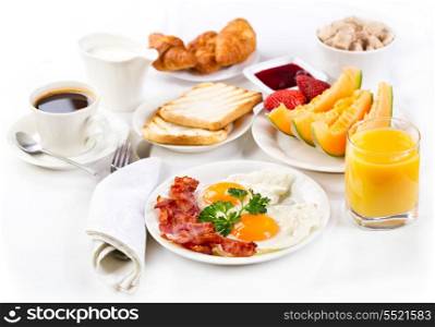 Breakfast with fried eggs, coffee, orange juice, croissant, toasts and fruits