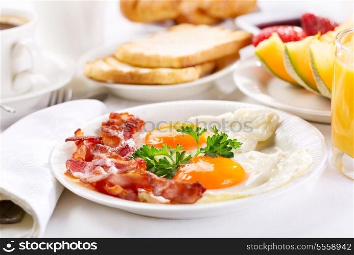 Breakfast with fried eggs, coffee, orange juice, toasts and fruits