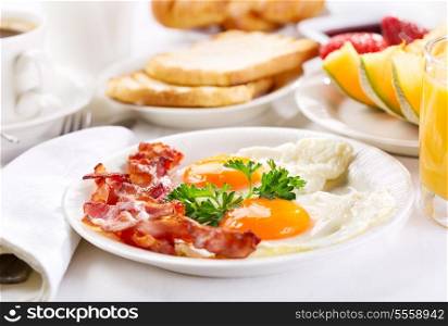 Breakfast with fried eggs, coffee, orange juice, toasts and fruits