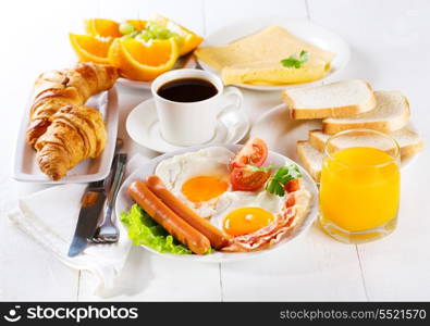 breakfast with fried eggs, croissants, juice, coffee and fruits