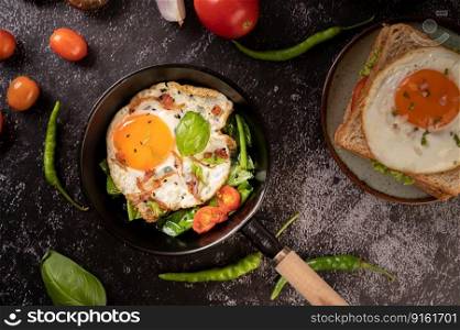 Breakfast with fried eggs, sausage, and ham in a pan with tomatoes. Chili and basil.