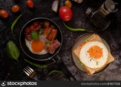 Breakfast with fried eggs, sausage, and ham in a pan with tomatoes. Chili and basil
