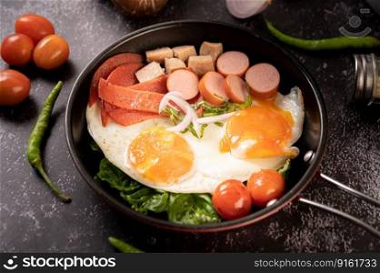 Breakfast with fried eggs, sausage, and ham in a pan with tomatoes. Chili and basil.