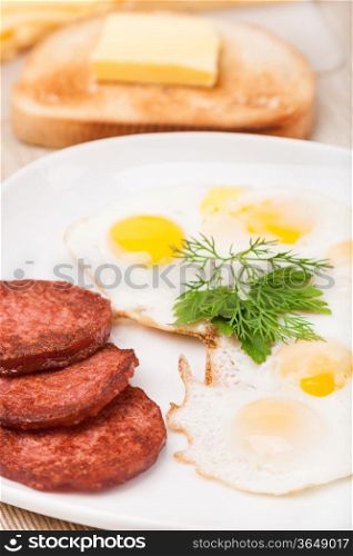 breakfast with fried eggs, sausage and toast on white plate