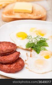 breakfast with fried eggs, sausage and toast on white plate