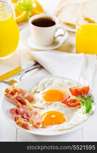 breakfast with fried eggs, toasts, juice, coffee and fruits