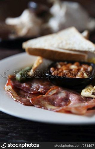 Breakfast with ham , fried egg and bread on wood background low key