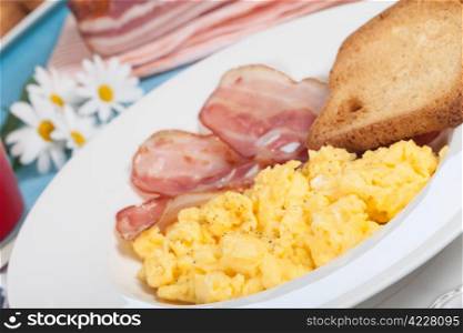 Breakfast with scrambled eggs and crispy bacon