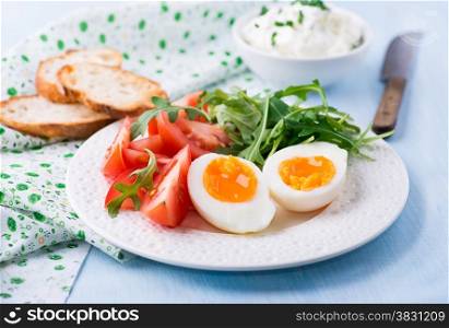 Breakfast with soft-boiled egg, arugula, soft cheese and tomatoes, selective focus