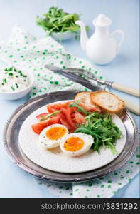 Breakfast with soft-boiled egg, arugula, soft cheese and tomatoes, selective focus