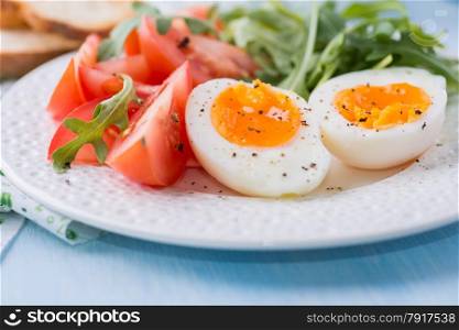 Breakfast with soft-boiled egg, arugula, soft cheese and tomatoes, selective focus