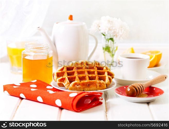 breakfast with waffles, honey and coffee on wooden table