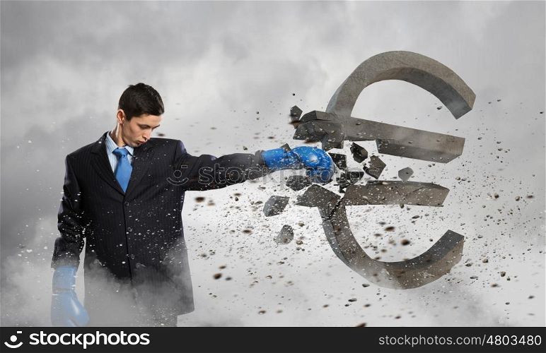 Breaking euro currency symbol. Young businessman in blue boxing gloves breaking euro sign