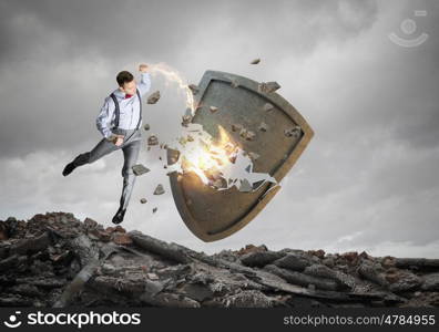 Breaking through security. Agressive businessman crashing with arm stone shield