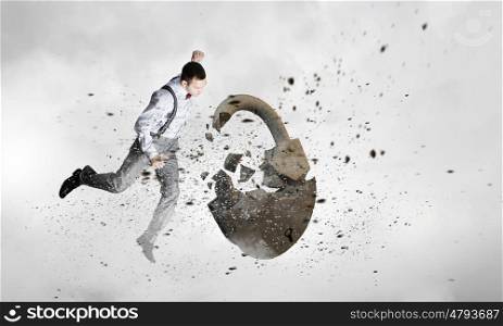 Breaking through security. Young angry businessman crashing stone lock with hand