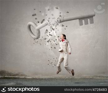 Breaking through security. Young angry businesswoman crashing stone key with hand