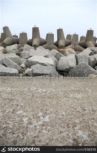 Breakwater outdoor - concrete tetrapods on the beach near a port under construction
