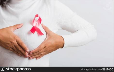 Breast cancer awareness healthcare and medicine concept. Close up Asian woman wear t-shirt she have pink breast cancer awareness ribbon on chest she hold breast by hand, isolated on white background
