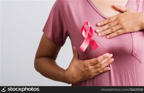Breast cancer awareness healthcare and medicine concept. Close up Asian woman wear pink t-shirt she have pink breast cancer awareness ribbon on chest she hold breast by hand, isolated white background