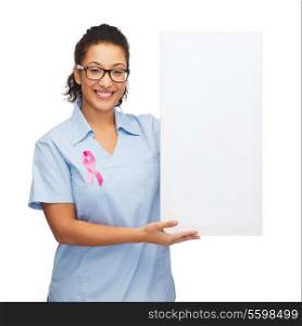 breast cancer awareness, healthcare and medicine concept - smiling african american doctor or nurse with pink ribbon and white blank board