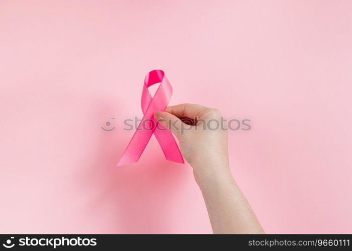 Breast Cancer Awareness Month. Woman’s hand holds pink ribbon. Health care concept, cancer control symbol. Copy space.. Breast Cancer Awareness Month. Woman’s hand holds pink ribbon. Health care concept, cancer control symbol. 