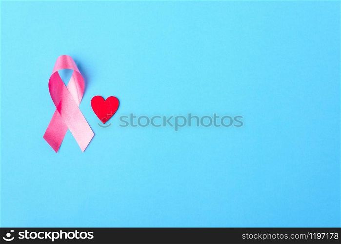 Breast cancer month concept, flat lay top view, pink ribbon and red Heart on blue background with copy space for your text