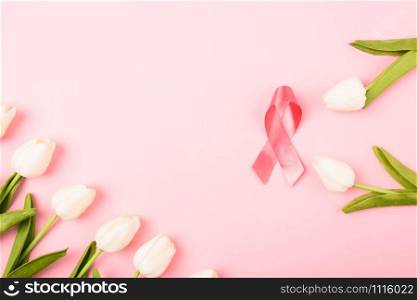 Breast cancer month concept, flat lay top view, pink ribbon and Tulip Flower on pink background with copy space for your text
