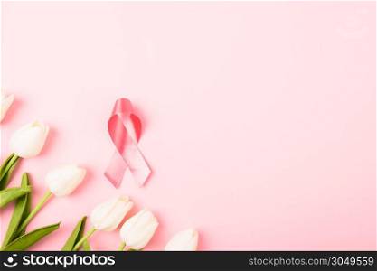 Breast cancer month concept, flat lay top view, pink ribbon and Tulip Flower on pink background with copy space for your text