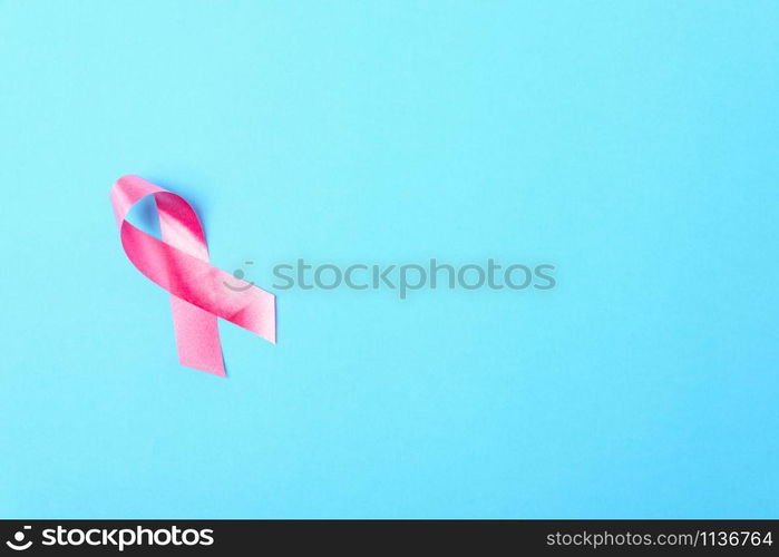 Breast cancer month concept, flat lay top view, pink ribbon on blue background with copy space for your text