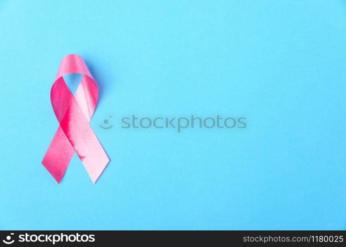 Breast cancer month concept, flat lay top view, pink ribbon on blue background with copy space for your text