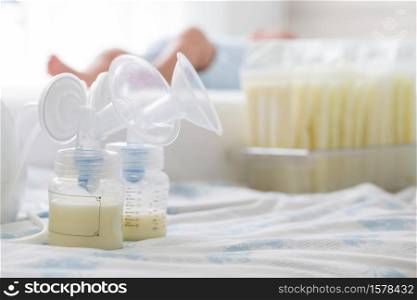Breast milk frozen in storage bag and baby lying on background