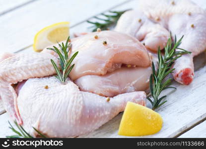 Breast wings and legs uncooked chicken meat marinated with ingredients for cooking / Fresh raw chicken with rosemary lemon herbs and spices