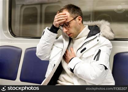 Breathing, respiratory problem, asthma attack, chest pain, dizziness concept. Sick man in subway train does not feel well, he has problems with breathing and pressure, touching her forehead.