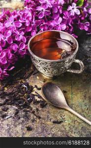 Brew tea in a stylish circle,branch of lilac on metallic background