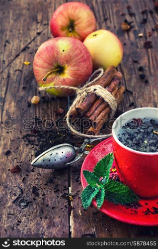 brew tea. Red Cup and saucer of herbal tea with apples and cinnamon sticks