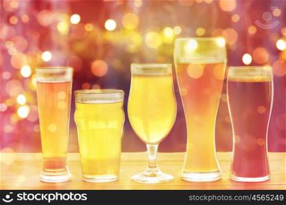 brewery, drinks and alcohol concept - close up of different beers in glasses on table over holidays lights background. close up of different beers in glasses on table