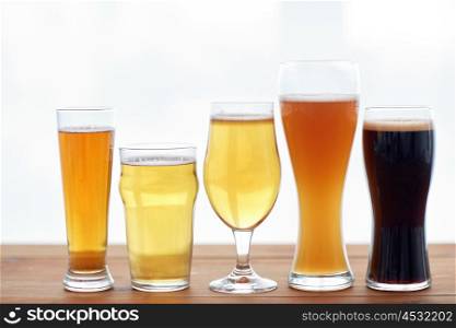 brewery, drinks and alcohol concept - close up of different beers in glasses on table